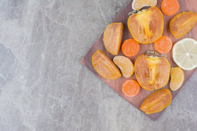 Tranches de kaki, citron, mandarine et bonbons à bord.