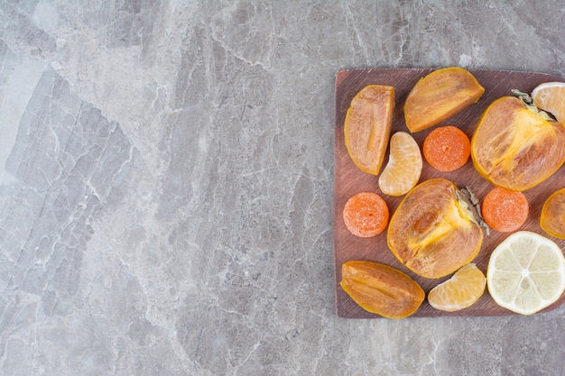 Tranches de kaki, citron, mandarine et bonbons à bord.