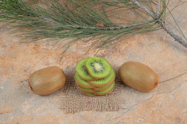 Tranches de kiwi et de kiwi sur une surface en marbre.