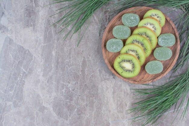 Tranches de kiwi et marmelades sur plaque en bois avec branche.