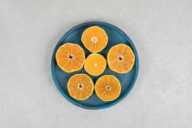 Tranches de mandarine fraîche sur plaque bleue