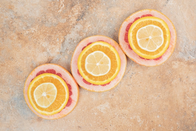 Tranches d'orange, de citron et de pamplemousse juteuses sur une surface en marbre.