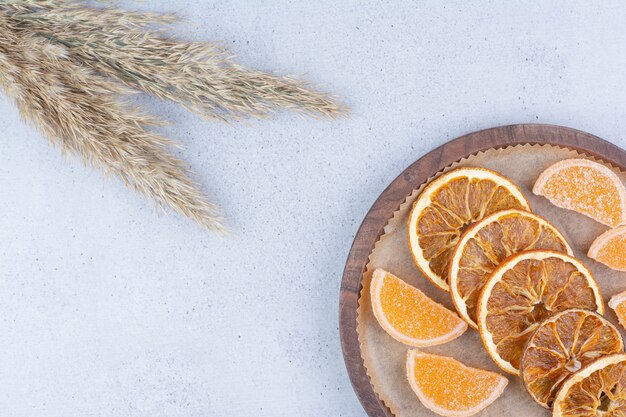 Tranches d'orange séchées et marmelades sur planche de bois.