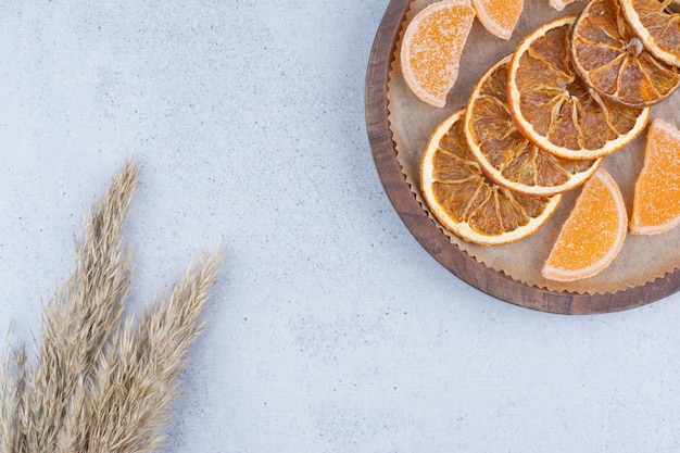 Tranches d'orange séchées et marmelades sur planche de bois.