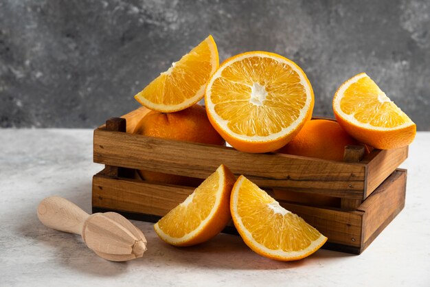Tranches d'oranges fraîches avec alésoir en bois sur marbre.