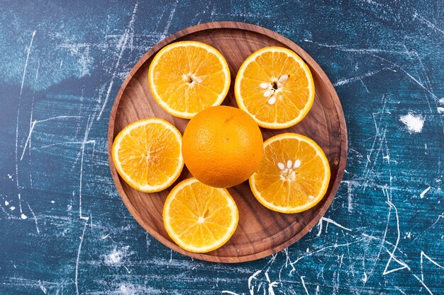 Tranches d'oranges et de mandarines sur un plateau en bois, vue du dessus