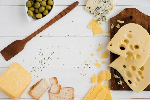 Tranches de pain aux olives; pain et fromage sur le bureau blanc