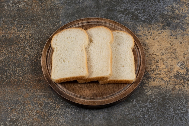 Tranches de pain blanc fait maison sur planche de bois.