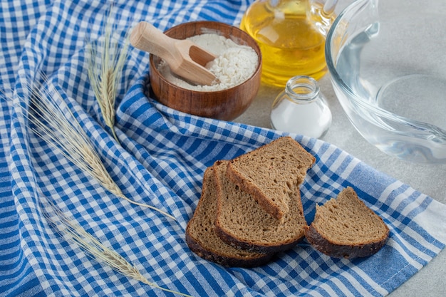 Tranches de pain brun avec bol de farine en bois.
