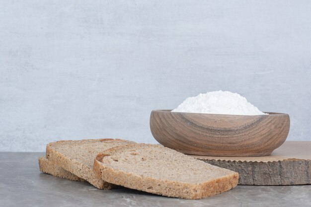 Tranches de pain brun avec de la farine sur une surface en marbre