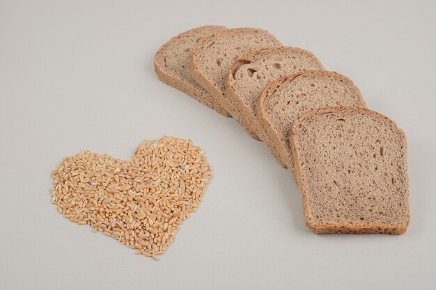 Tranches de pain brun frais avec des grains d'avoine sur fond blanc. Photo de haute qualité