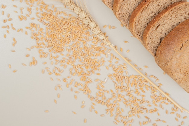 Photo gratuite tranches de pain brun frais avec des grains d'avoine sur une surface blanche