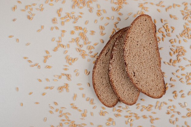 Tranches de pain brun frais avec des grains d'avoine sur une surface blanche