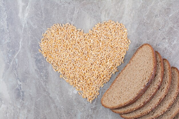 Tranches de pain brun avec des grains d'avoine sur une surface en marbre