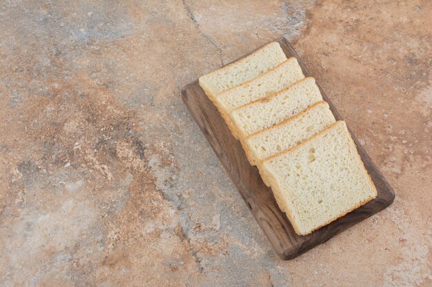 Tranches de pain grillé blanc sur planche de bois