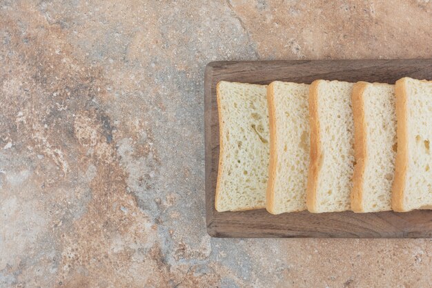 Tranches de pain grillé blanc sur planche de bois