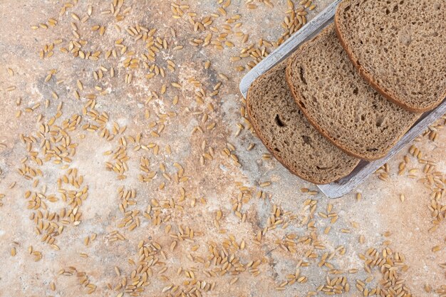 Tranches de pain noir avec des grains d'orge sur une surface en marbre