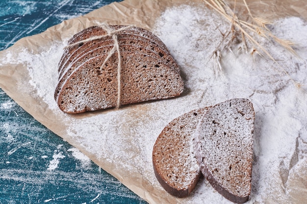 Tranches de pain noir sur table bleue.