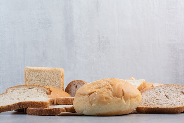 Tranches de pain et petit pain aux graines de sésame sur une feuille de papier