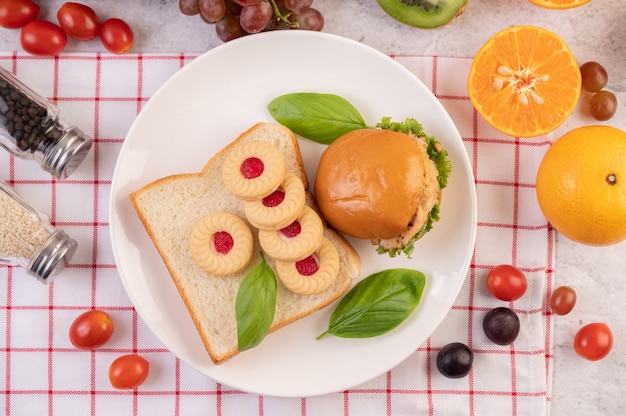 Tranches de pain, petits pains farcis et hamburgers sur une assiette blanche.