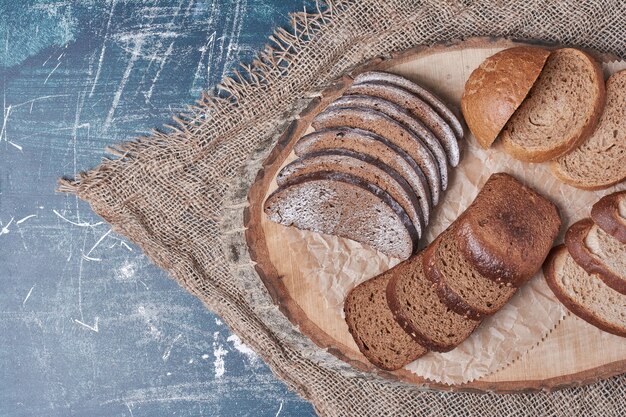 Tranches de pain sur planche de bois sur table bleue.