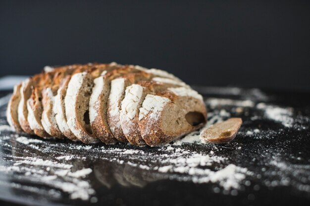 Tranches de pain rustiques avec de la farine saupoudrée sur un comptoir de cuisine réfléchissant