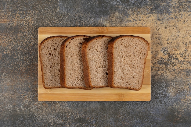 Tranches de pain de seigle frais sur planche de bois