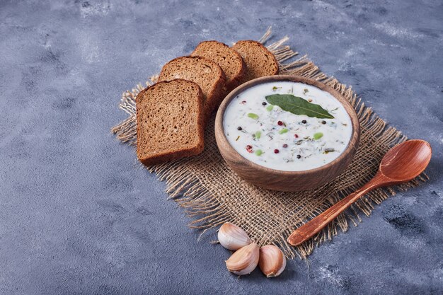 Tranches de pain avec une tasse de soupe au yogourt et de l'ail.