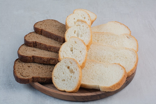 Tranches de pains frais blancs et bruns sur fond de marbre.