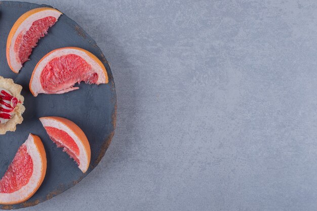 Tranches de pamplemousse frais avec cookie sur plaque en bois gris