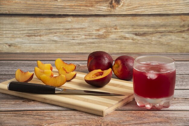 Tranches de pêche sur une planche à découper en bois avec une tasse de boisson glacée