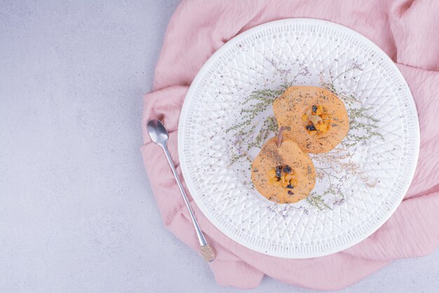 Tranches de poire pelées et cuites au four avec des herbes et épices dans une assiette blanche