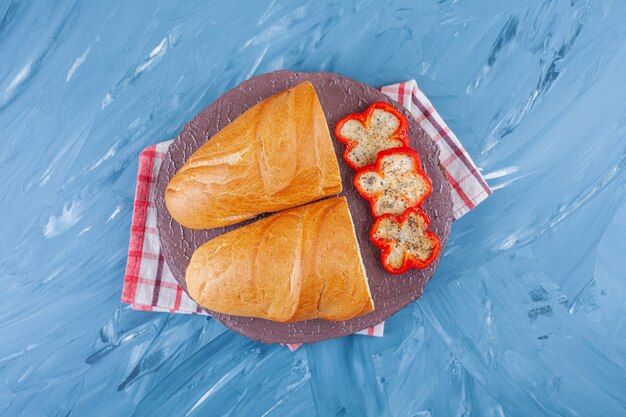 Tranches de poivre et de pain sur une planche sur un torchon, sur la table bleue.