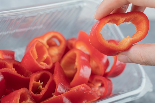 Tranches de poivrons rouges doux sur plaque en plastique.