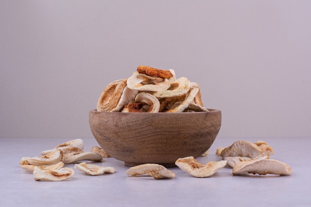 Tranches de pomme sèches dans une tasse en bois sur une surface grise