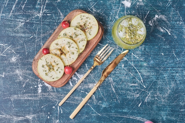 Tranches De Pomme Avec Une Tasse De Boisson Sur Bleu.