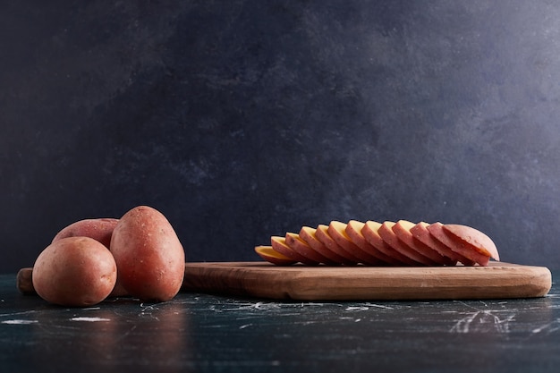 Tranches de pomme de terre sur planche de bois.