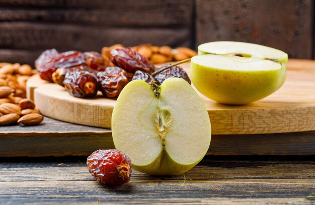 Tranches de pommes aux dattes et amandes sur bois et planches à découper vue latérale sur carreaux de pierre et bois