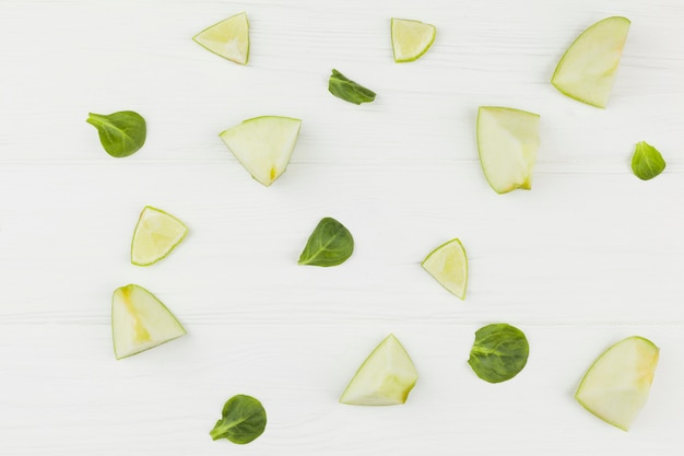 Tranches de pommes citron vert et feuilles vertes sur fond blanc