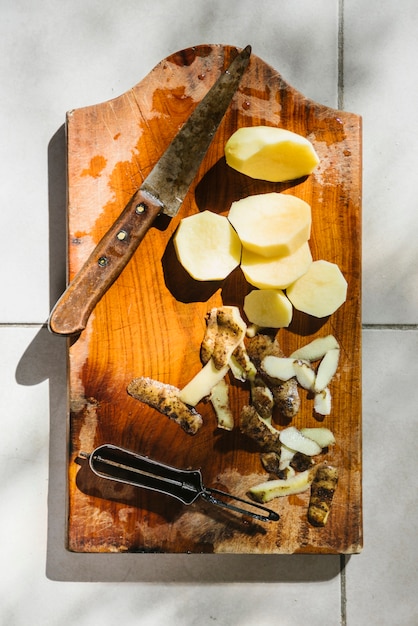 Tranches de pommes de terre au couteau sur une planche à découper en bois