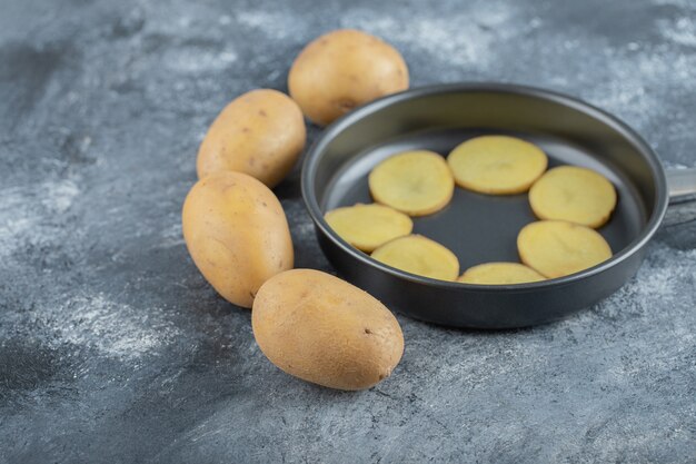 Tranches de pommes de terre à l'intérieur de la casserole sur fond gris. Photo de haute qualité