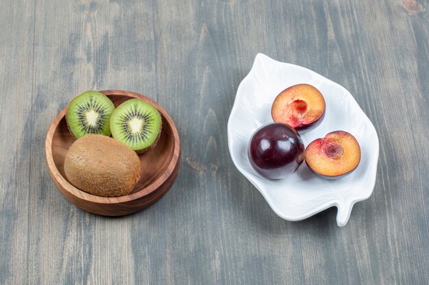 Tranches de prunes fraîches avec kiwi juteux sur une table en bois