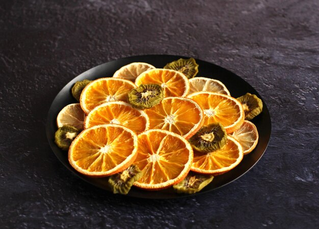 Tranches séchées de kiwi citron orange sur fond sombre