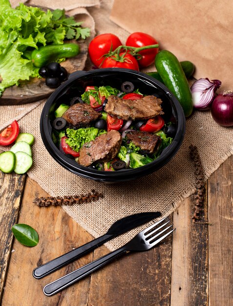 Tranches de steak de bœuf grillé avec salade verte, tomates et olives