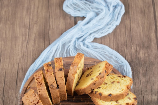 Photo gratuite tranches de tarte molle avec sultane noir sur planche de bois.