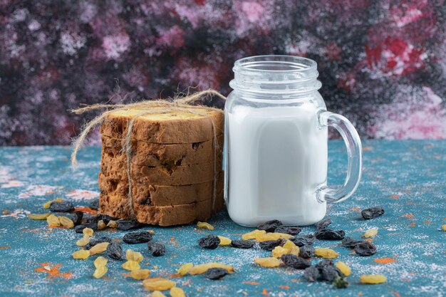 Tranches de tarte Sultana et un pot de lait sur bleu.