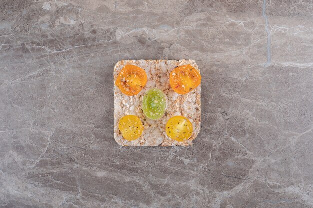 Tranches de tomates assaisonnées avec gâteau de riz en dessous, sur la surface en marbre