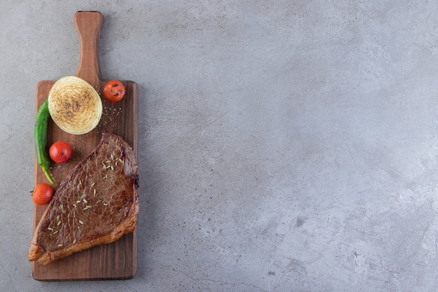 Tranches de viande fraîche avec des légumes frais placés sur un fond de pierre.