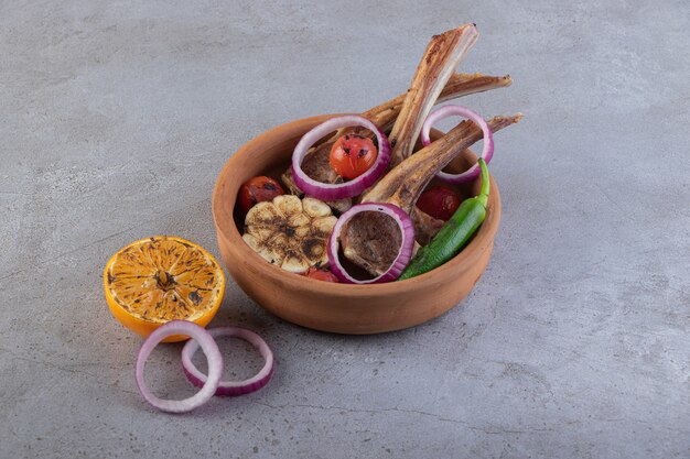 Tranches de viande fraîche avec des légumes frais placés sur une table en pierre.