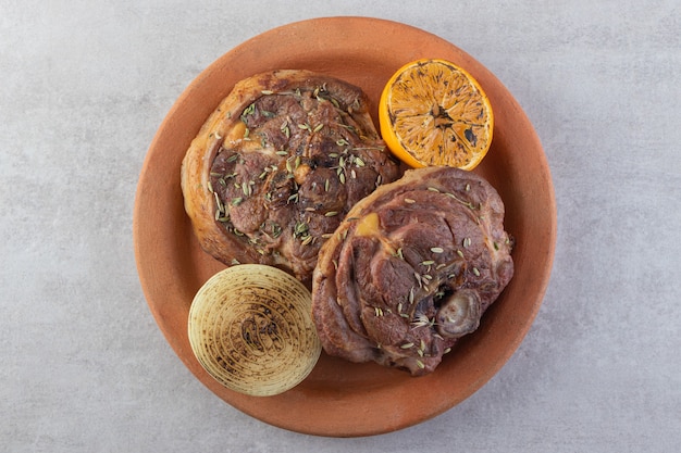 Tranches de viande fraîche avec des légumes frais placés sur une table en pierre.